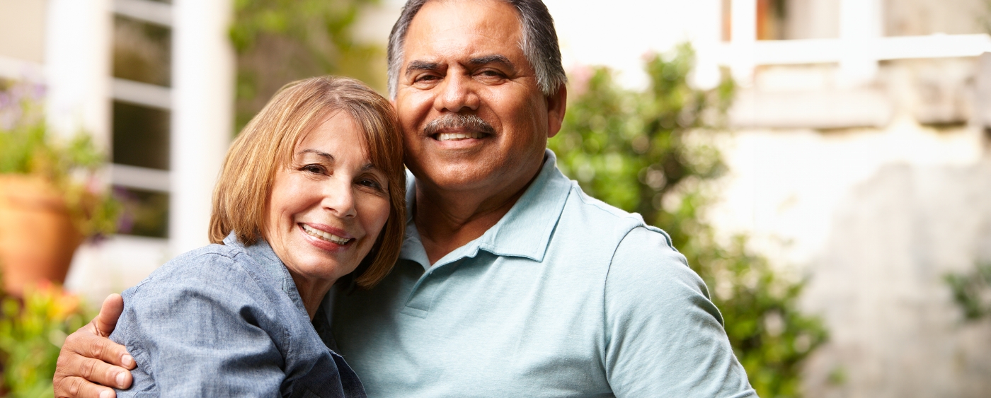 Older couple smiling on their porch after seeing their dentist in Sumner