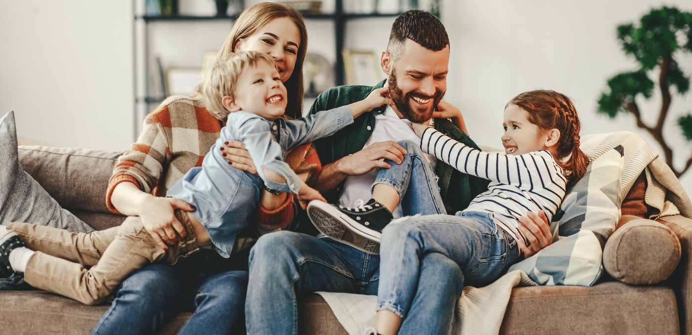 Family of four laughing on their couch