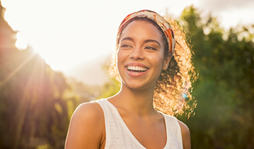 Woman with long curly hair in a ponytail smiling in the sun