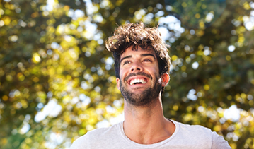 Young man with curly brown hair smiling in the sun